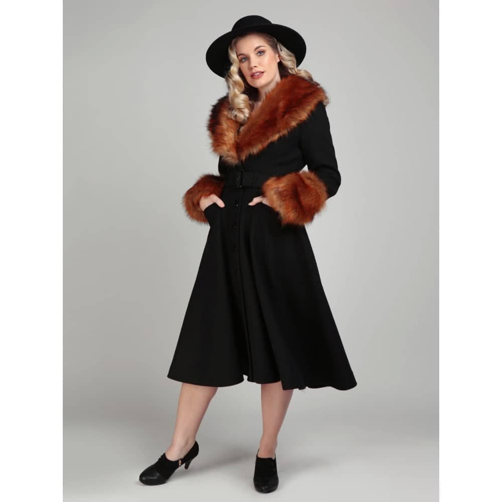 Fantastisk 1950'er sort frakke fra Collectif  med imiteret pels. Den luksuriøse imiterede pelskrave og manchetter sammen den flotte markerede talje og swingskørt skaber en smuk silhuet